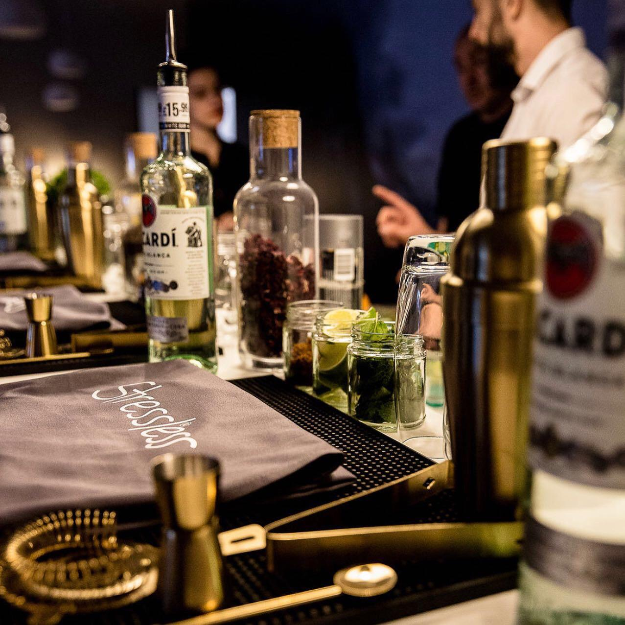 Masterclass bar detail with spirits, herbs, tools and branded apron arranged for cocktail making