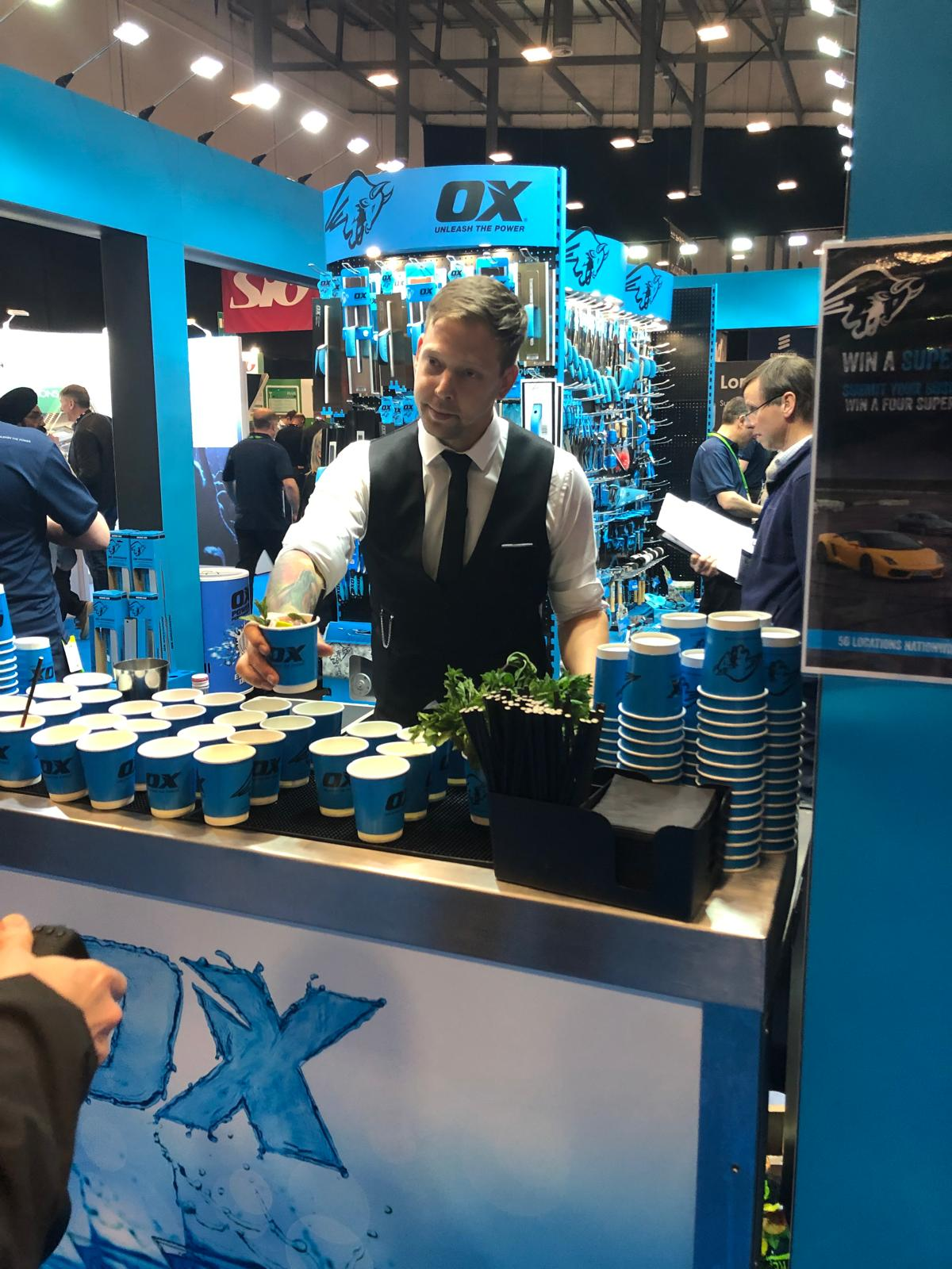Bartender serving OX branded drinks to delegates at a trade show stand activation