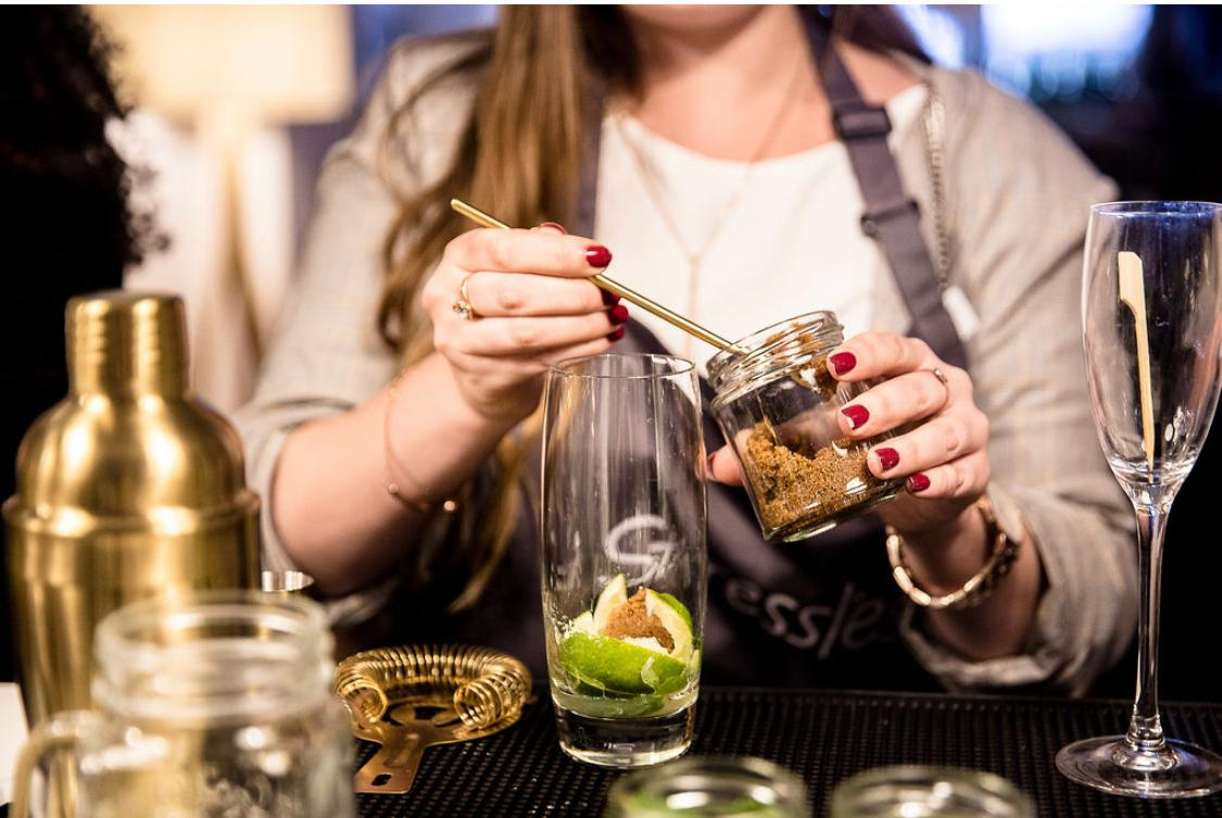 Guest building a cocktail with fresh lime and garnish during a cocktail masterclass