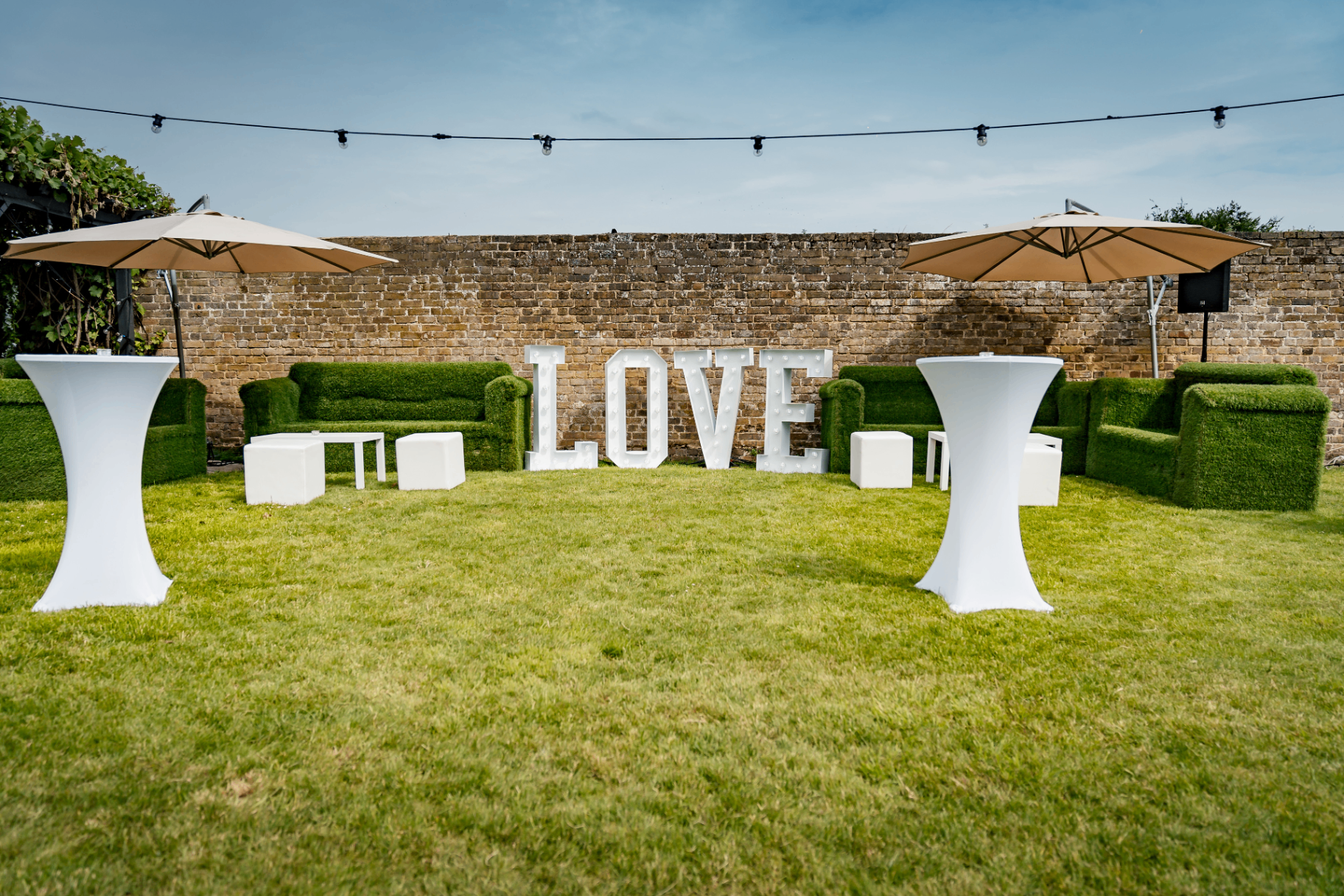 Outdoor wedding lounge seating with illuminated LOVE letters on the lawn