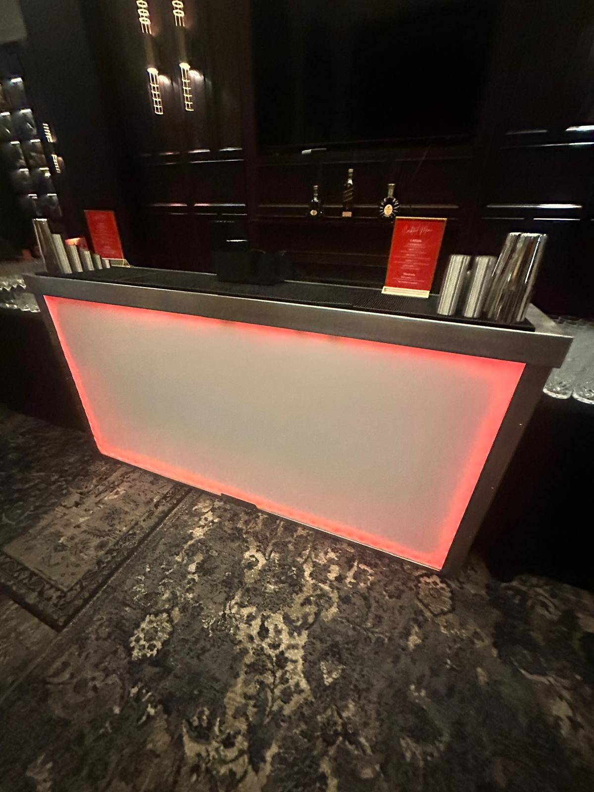 Red-lit LED mobile bar set up inside a dark luxury hotel lounge