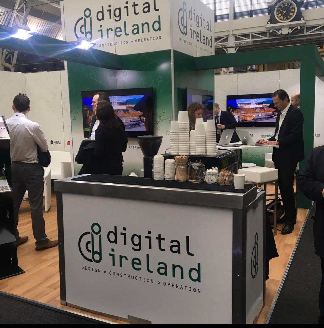 Digital Ireland branded exhibition coffee bar with stacked takeaway cups and espresso service ready for delegates