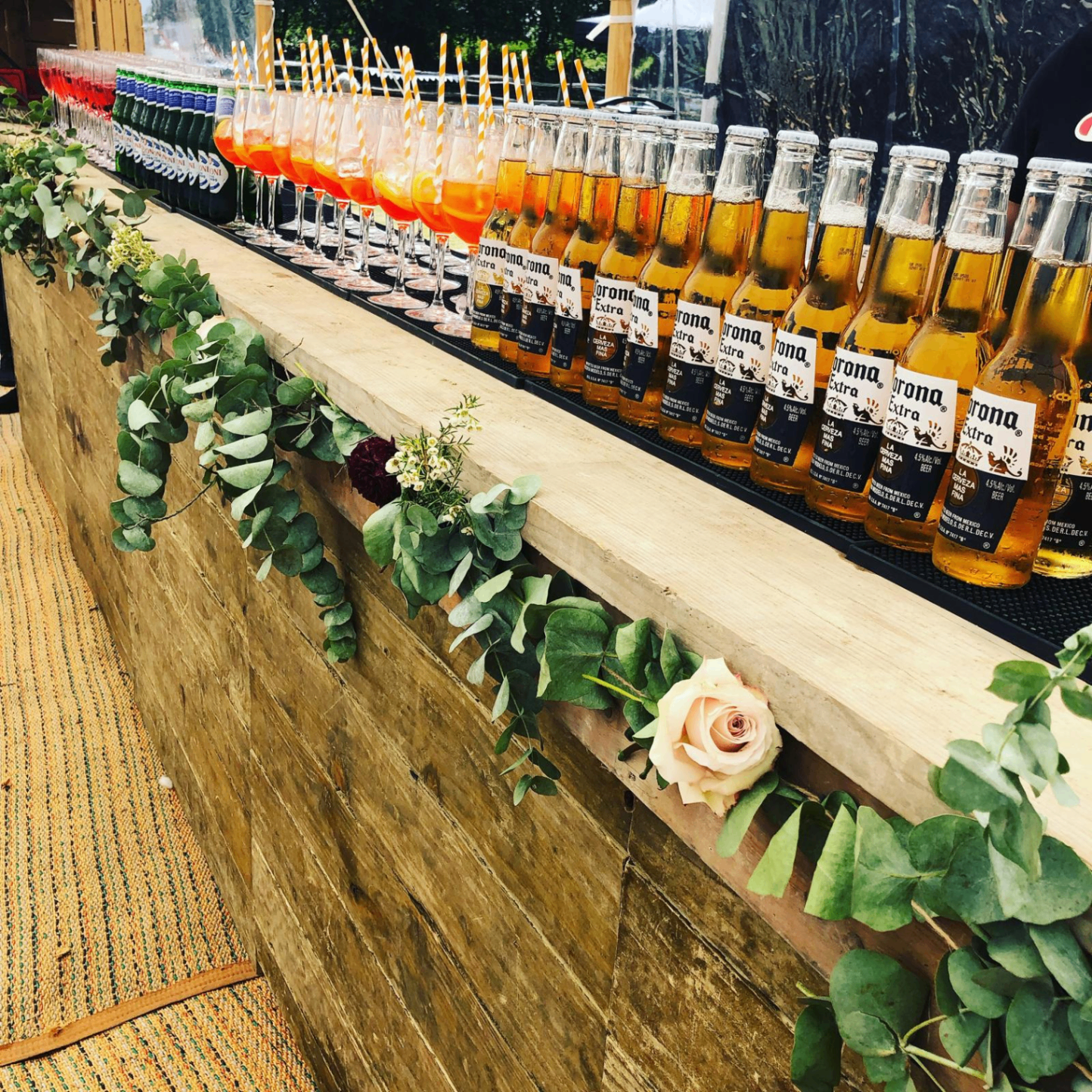 Rustic wooden mobile bar serving Corona and Aperol Spritz at a wedding