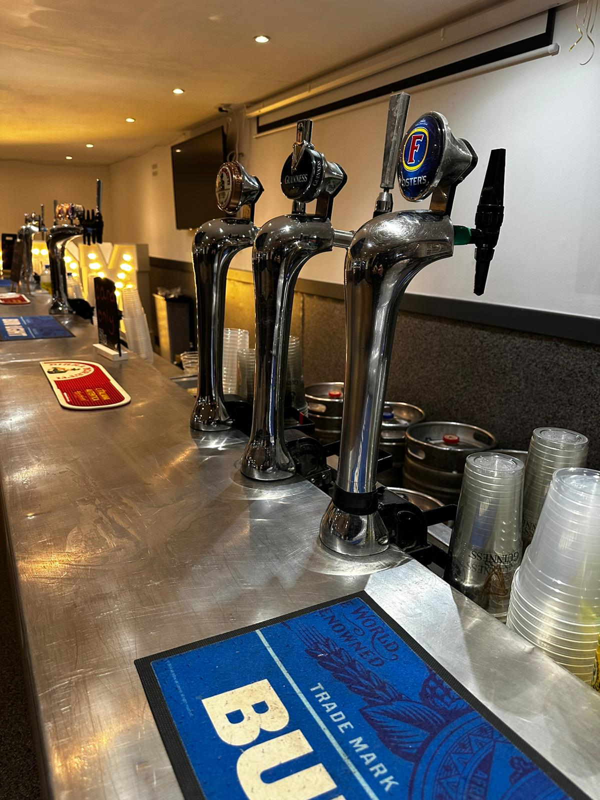 Mobile draft bar with chrome Foster's, Guinness and lager keg fonts on a stainless steel counter