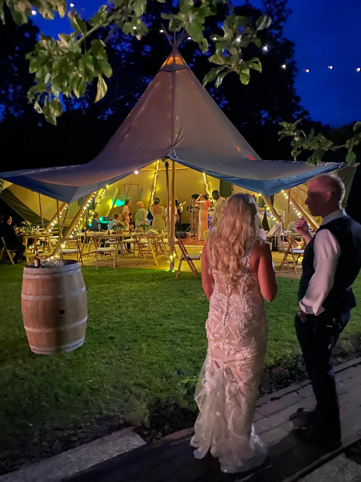 Bride and groom watching the evening band at a fairy-lit tipi wedding reception