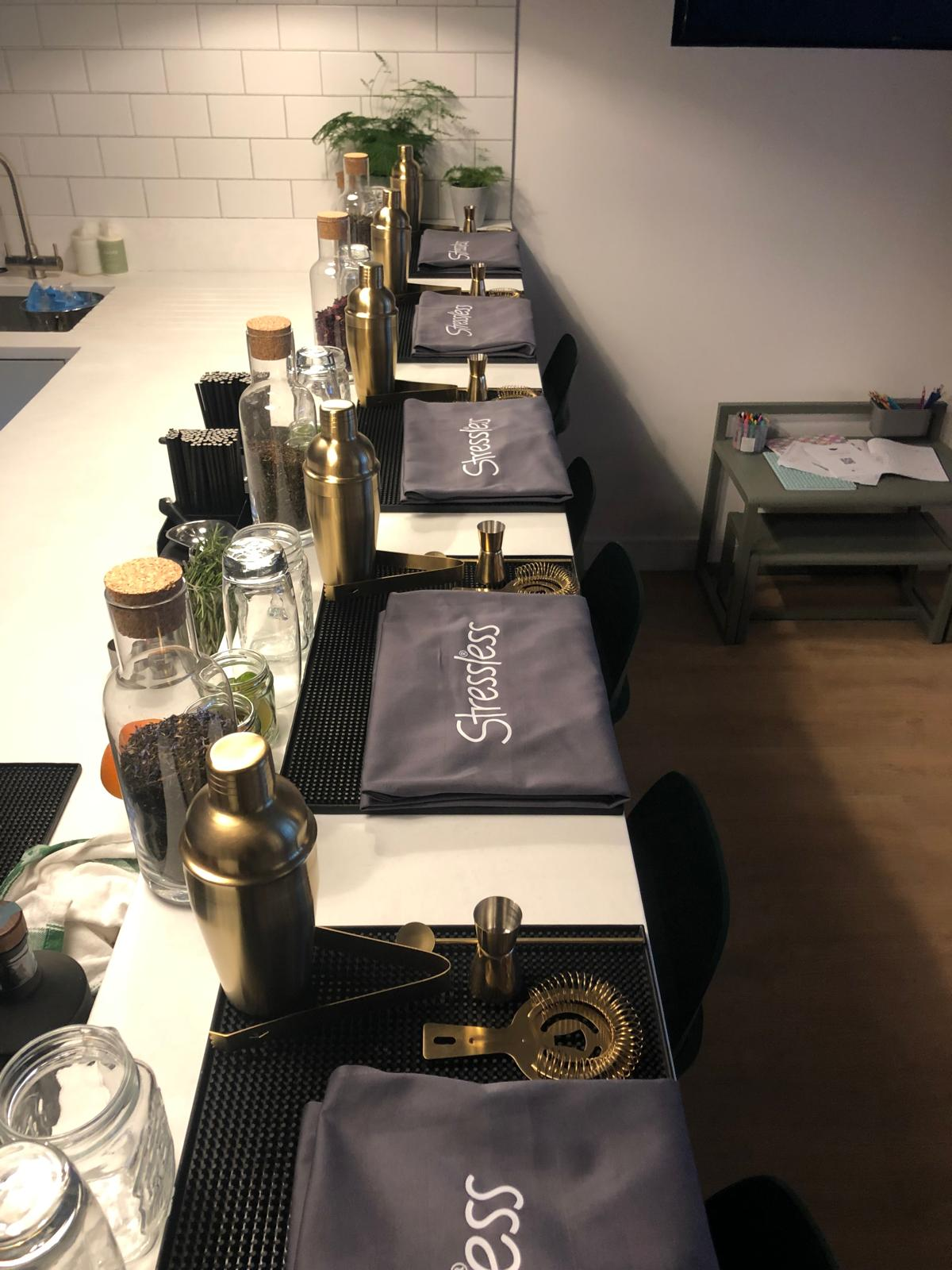 Cocktail masterclass station setup with branded aprons, shakers and bar tools laid out for guests