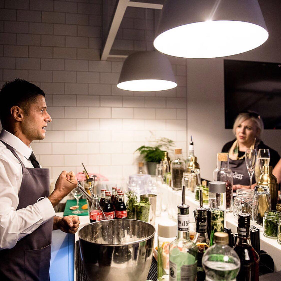 Cocktail tutor leading a hands-on class while guests watch from the bar station
