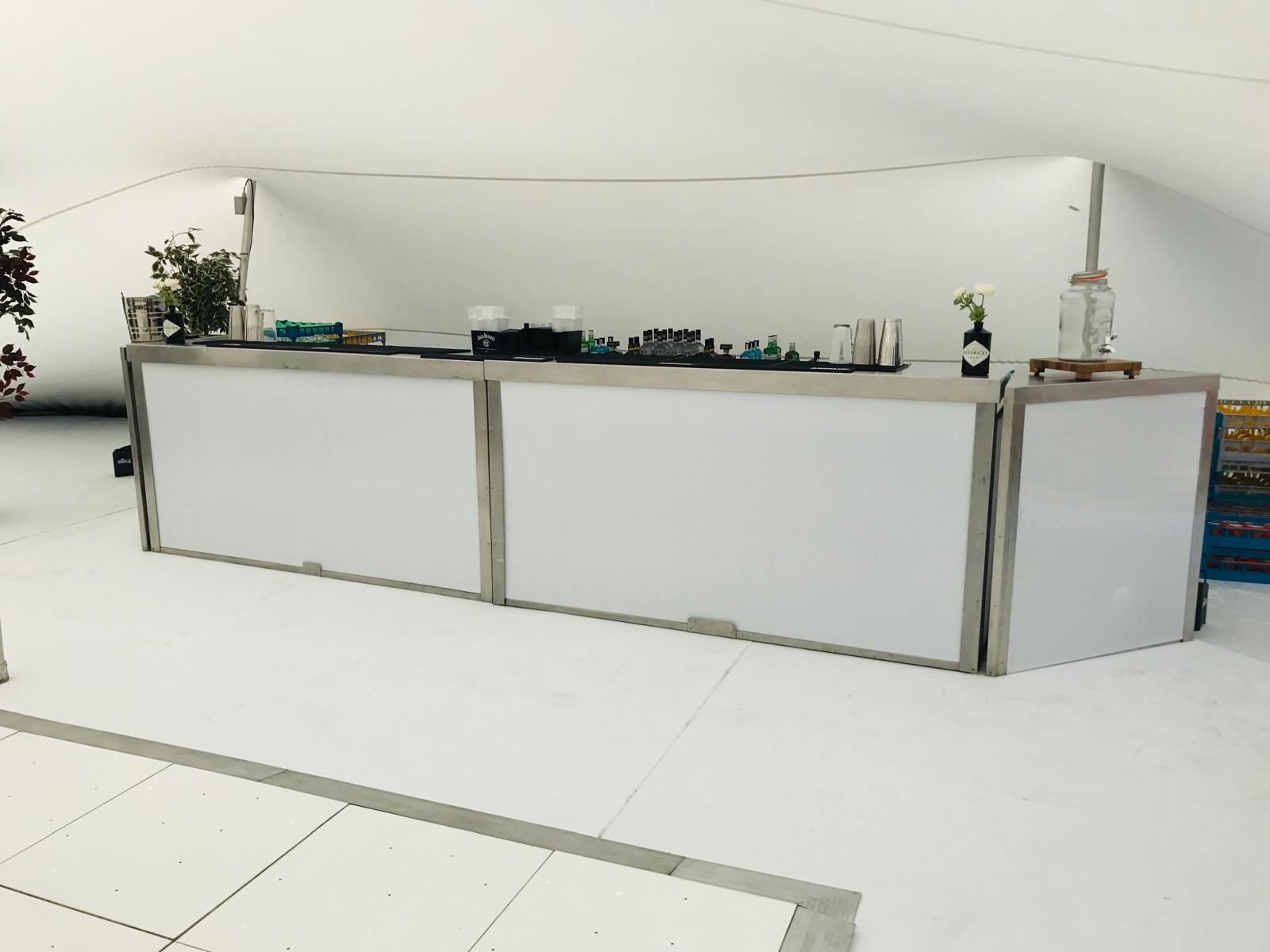 Long white modular mobile bar from our hire catalogue built inside a bright event marquee